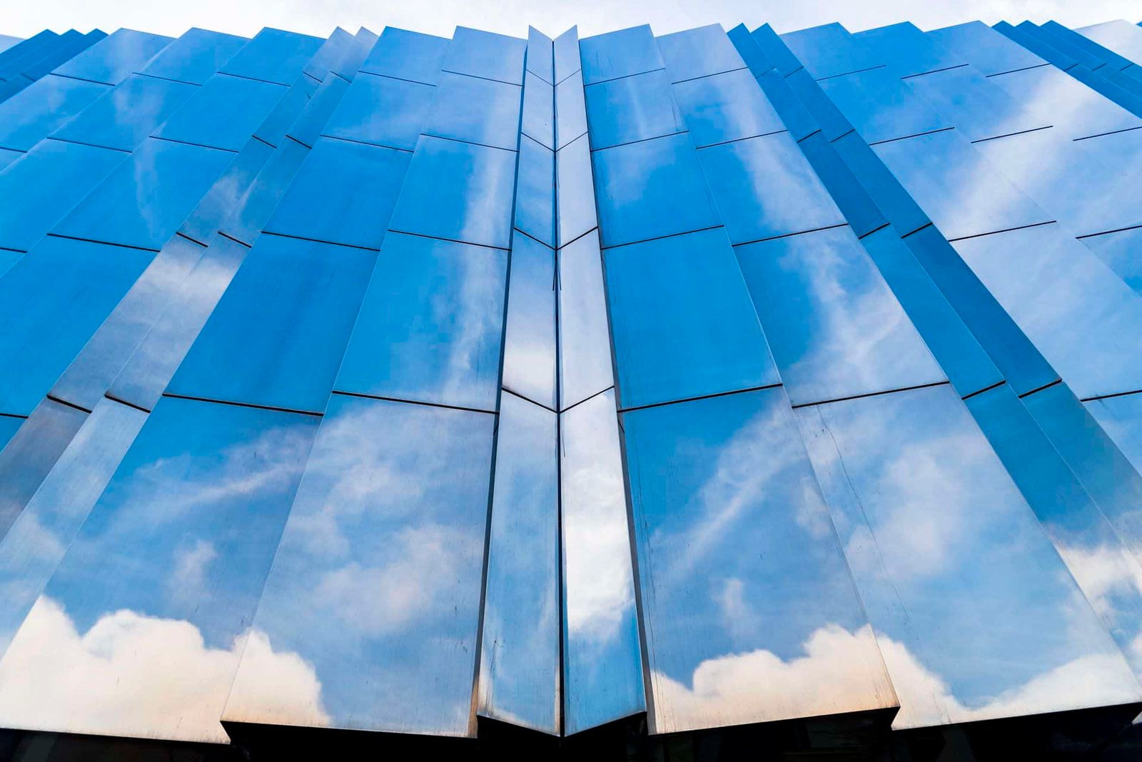A blue building with clouds reflected in it.