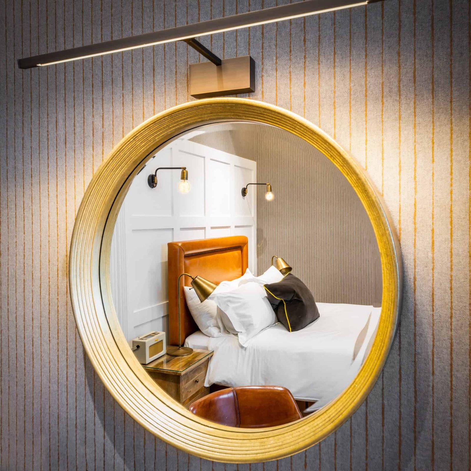 A round mirror hangs above a bed in a bedroom.