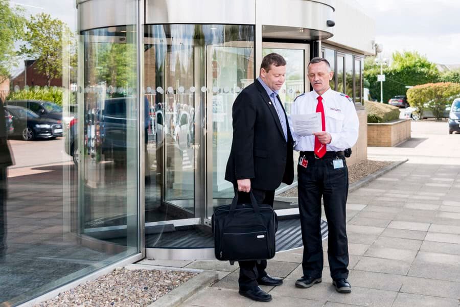 Two men standing in front of a glass door.