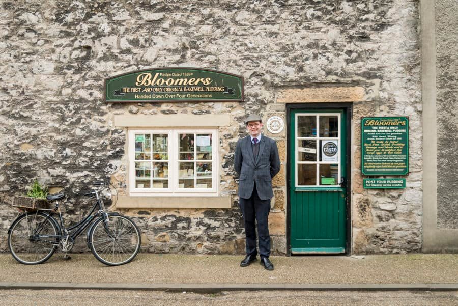 A man in a suit standing in front of a stone building.