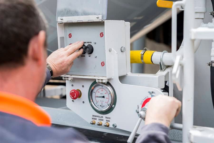 A man is adjusting a gauge on a tank.