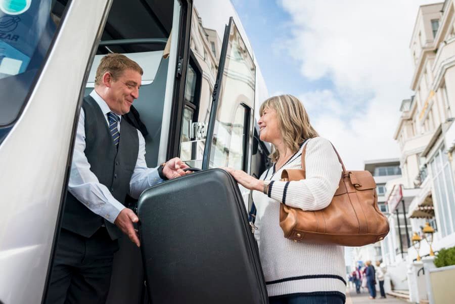 A man and woman boarding a bus with luggage.