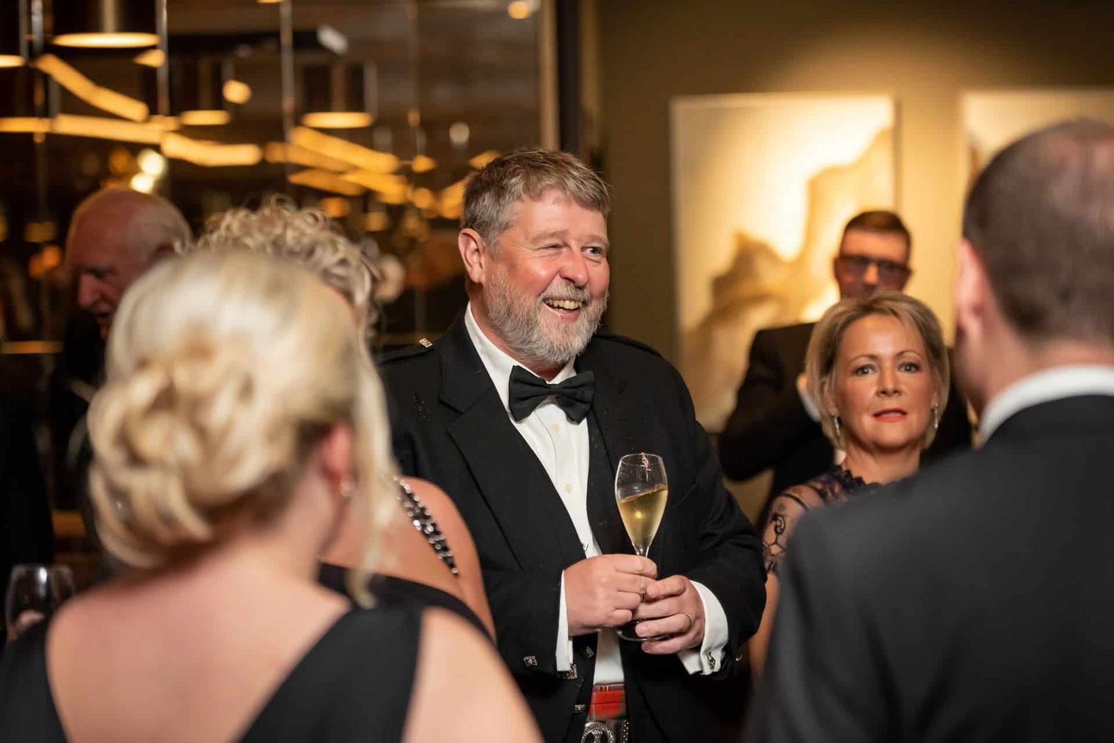 A man in a tuxedo is talking to a group of people.