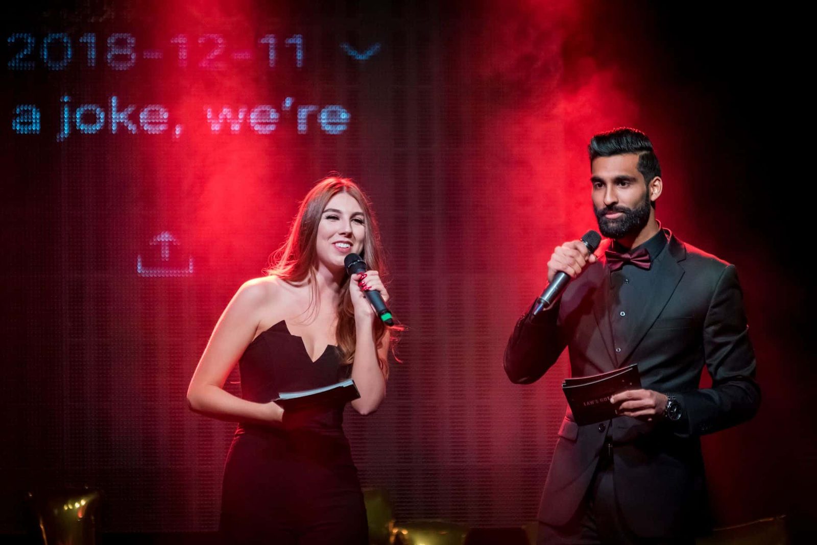 A man and woman standing on stage with a microphone.