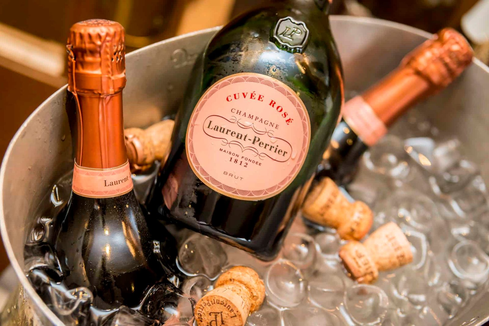 Two bottles of champagne sitting in a bucket of ice.