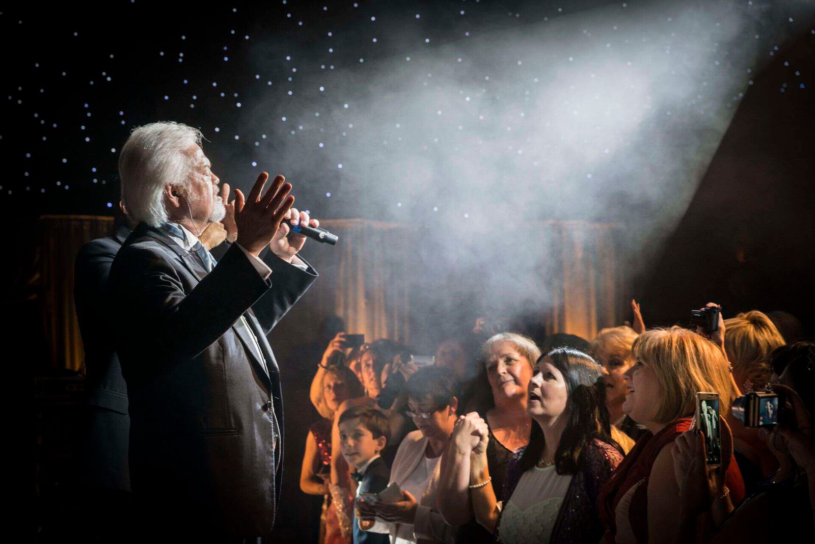 A man singing into a microphone in front of a crowd.