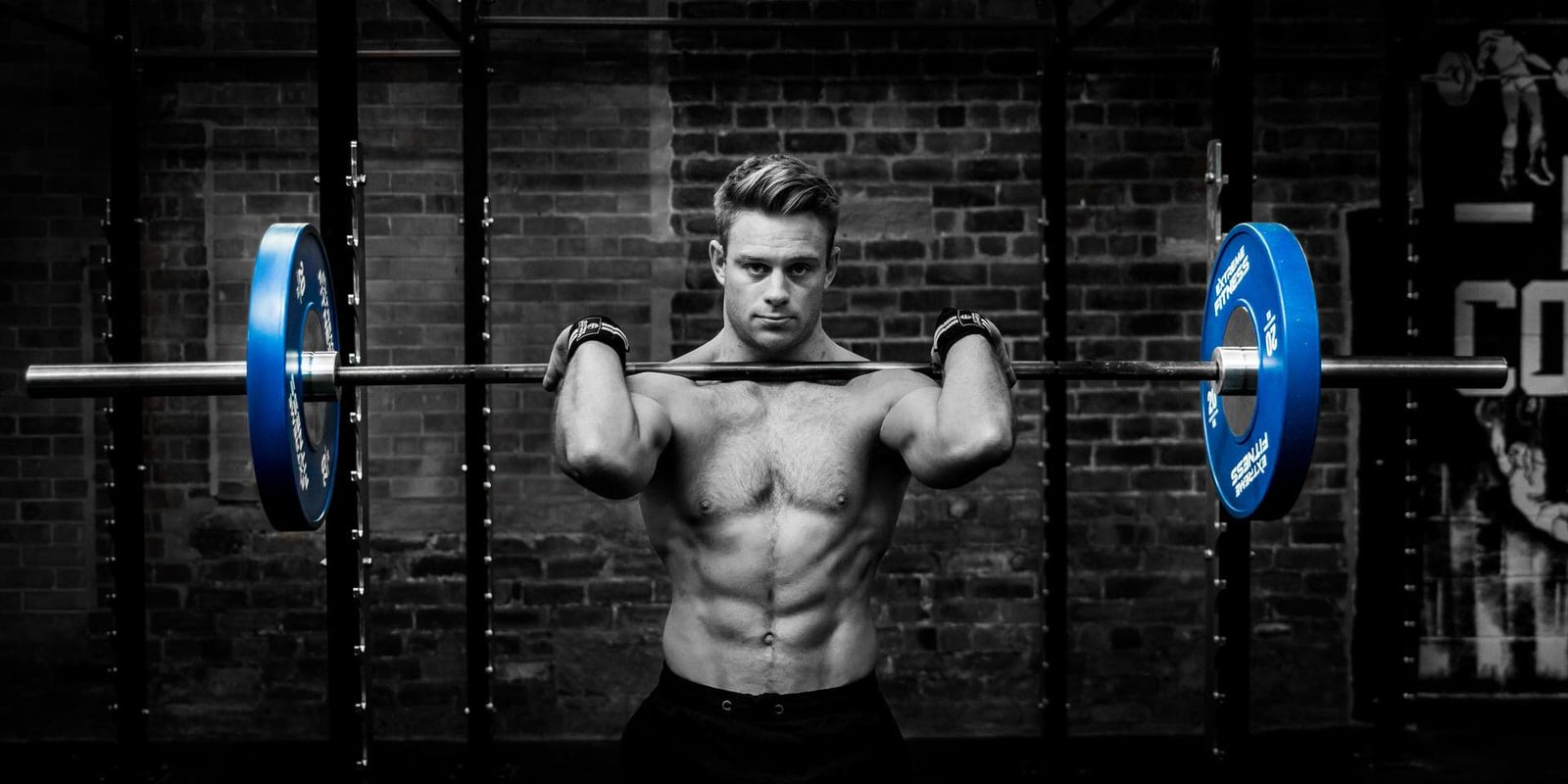 A man lifting a barbell in a gym.