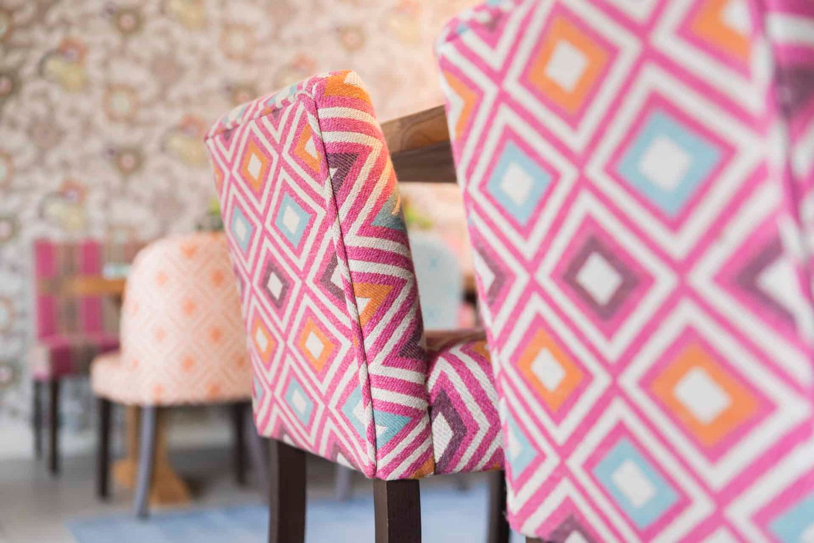 Chairs in a dining room with colorful patterned upholstered backs.