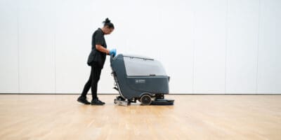 A woman cleaning a floor with a machine.