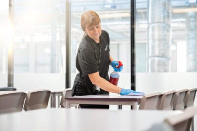 A woman cleaning a table in a classroom.