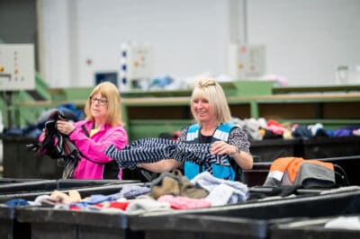Two women sorting clothes in a warehouse.