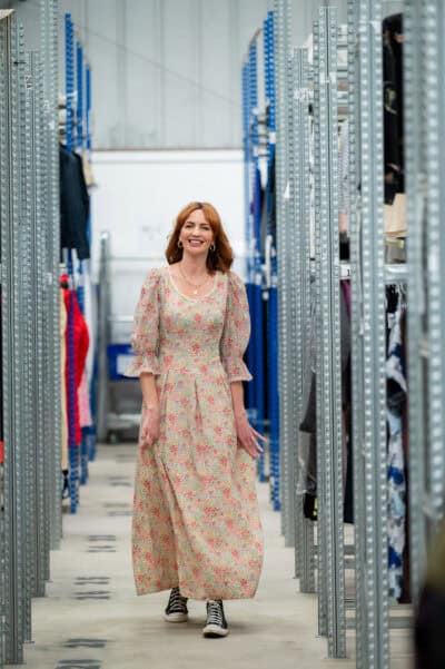A woman in a floral dress walking through a clothing store.
