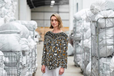 A woman standing in a warehouse full of clothes.