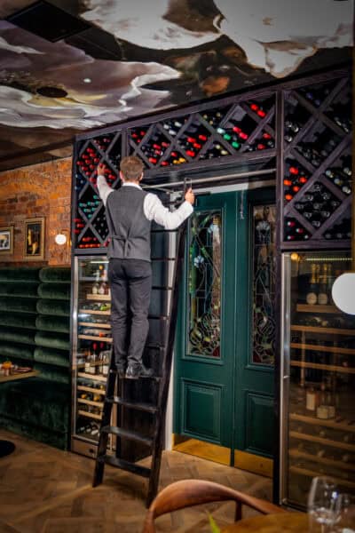 A man standing on a ladder in a restaurant.