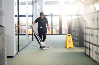 A man cleaning a hallway with a vacuum.