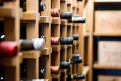 A row of wine bottles in a wooden rack.