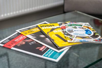 A glass coffee table with magazines on it.