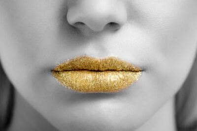 A close up of a woman's lips with gold lipstick.