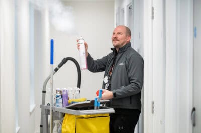 A man holding a steam cleaner in a hallway.