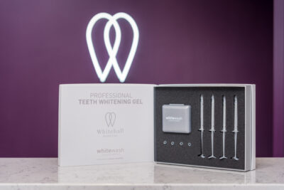 A box with a toothbrush and whitening kit in front of it.