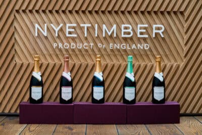 Four bottles of champagne in front of a sign that says nyetimber product to england.