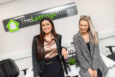 Two women standing in front of a sign that says the leasing room.