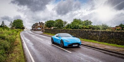 A blue sports car driving down a country road.
