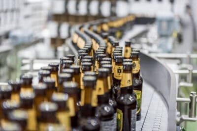 A line of beer bottles on a conveyor belt.