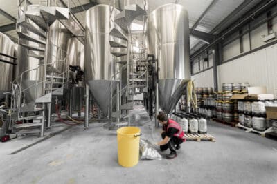 A woman is kneeling down in a brewery.