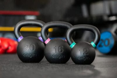 Three kettlebells on a table in a gym.