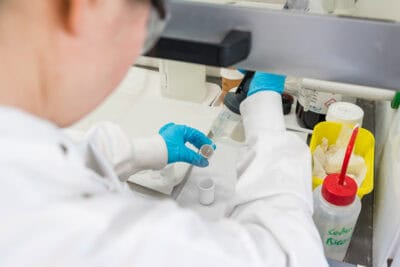 A person in a lab coat is preparing a sample.
