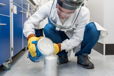 A man in a lab coat is putting a container on the floor.