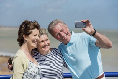 Three older people taking a selfie at the beach.
