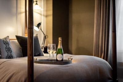 A bed with a bottle of champagne on a tray.