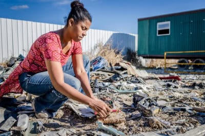 A woman kneeling down in front of a pile of debris.