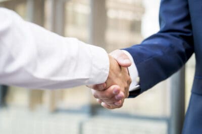 Two businessmen shaking hands in front of a building.