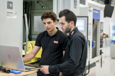 Two men looking at a laptop in a factory.
