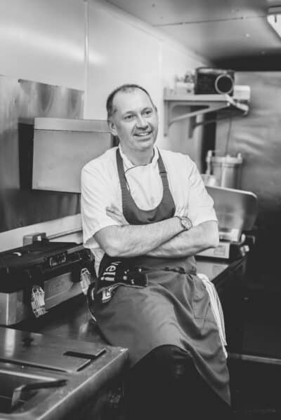 A black and white photo of a chef in a kitchen.