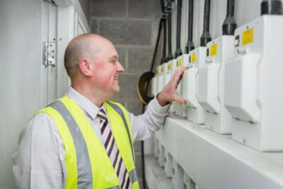 A man in a safety vest looking at electrical equipment.