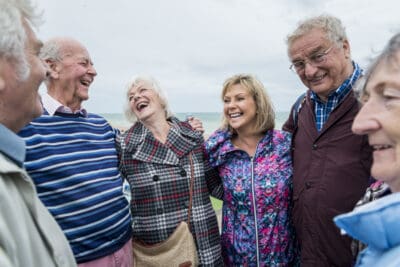 A group of older people laughing together on the beach.