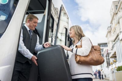A man and woman boarding a bus with luggage.