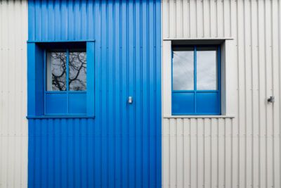 A blue and white building with two windows.