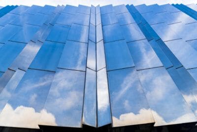 A blue building with clouds reflected in it.