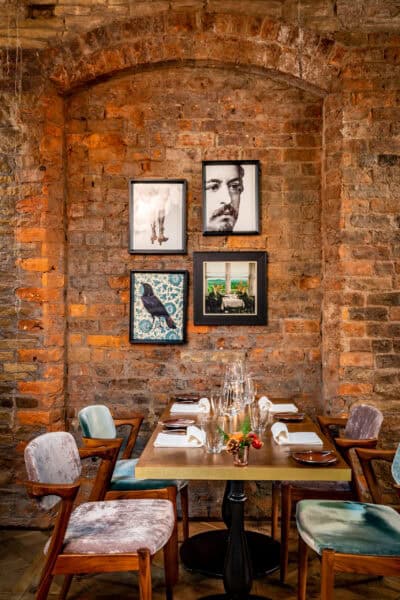 A dining room with a brick wall and framed pictures.