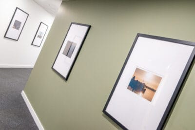 A hallway with framed pictures and a green wall.