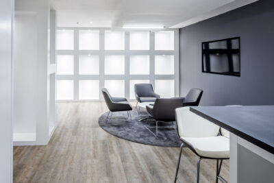 A modern office with grey walls and wooden floors.