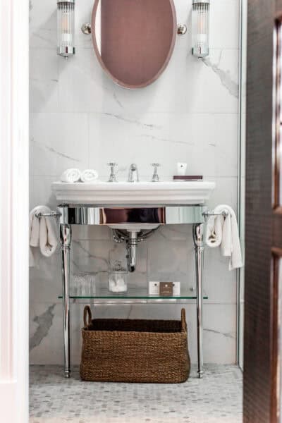A bathroom with a mirror, sink and basket.