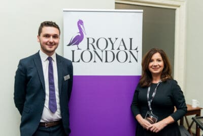 Two people standing in front of a royal london banner.