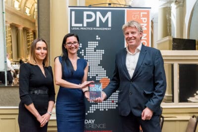 Three people standing in front of a banner that says lpm day.