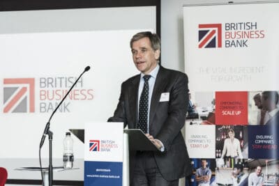 A man standing at a podium at a british business bank event.